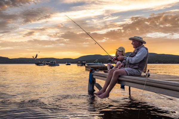 A grandfather and grandchild go fishing from a dock